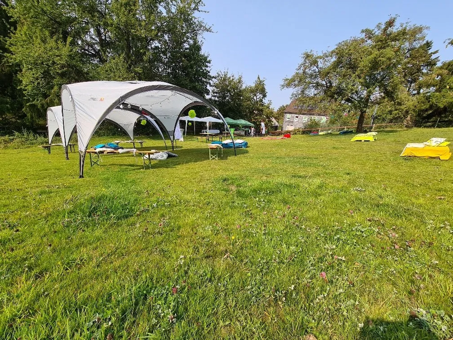 Mi Casa-Dein zu Hause - Familien- und Seniorenbetreuung - Ein großes weißes Veranstaltungszelt steht auf einer weiten grünen Wiese unter strahlend blauem Himmel.