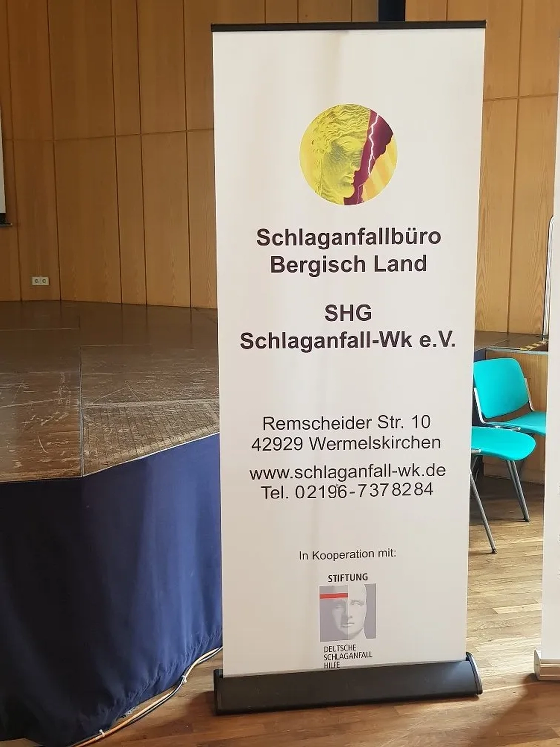 Mi Casa-Dein zu Hause - Familien- und Seniorenbetreuung - Ein Informationsbanner für das „Schlaganfallbüro Bergisch Land“, eine Beratungsstelle für Schlaganfallbetroffene, steht in einem Raum.